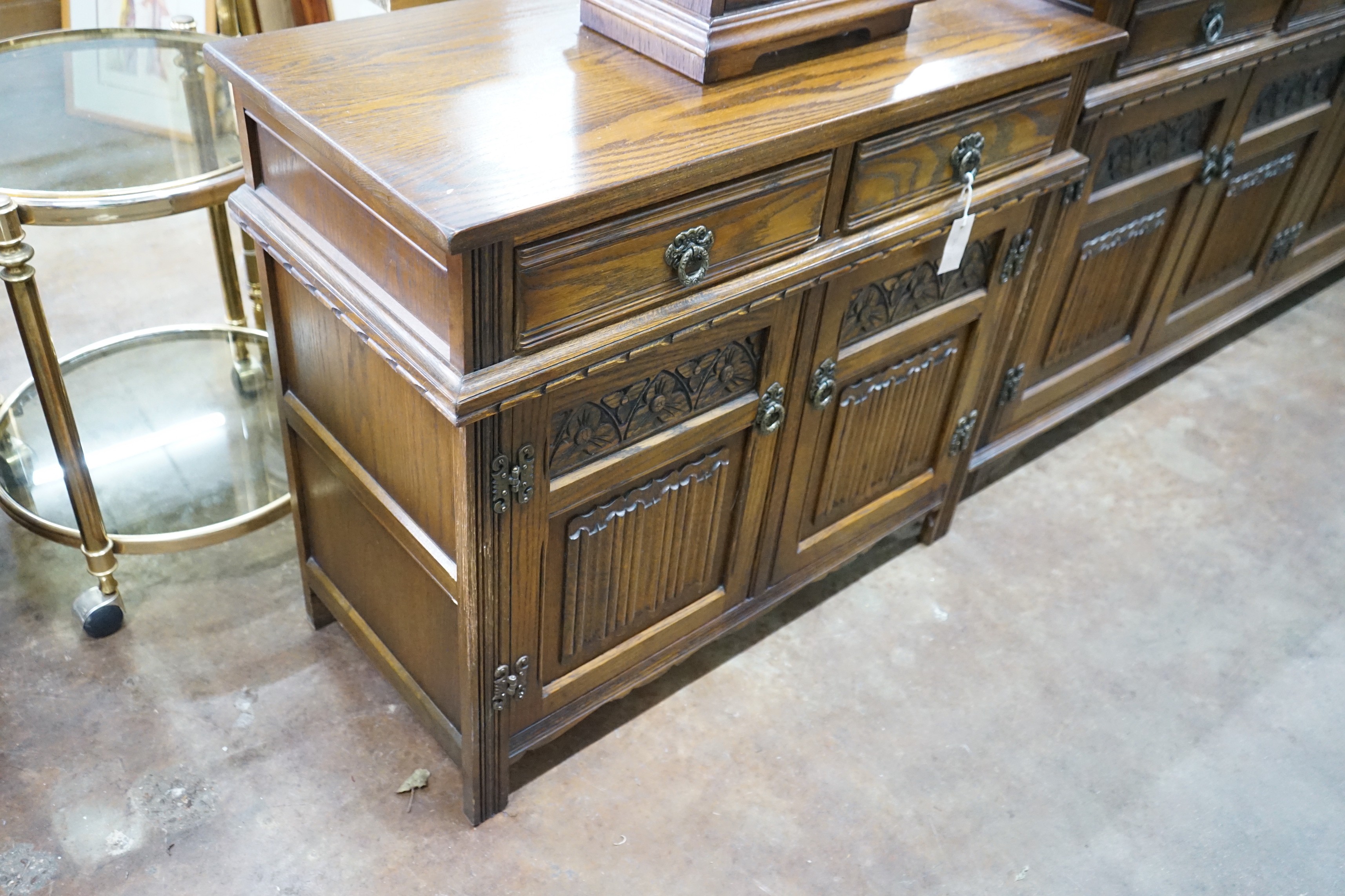 A reproduction 18th century style carved and linen fold moulded oak side cabinet and matching media cabinet, larger width 93cms, depth 43cms height 81cms.
